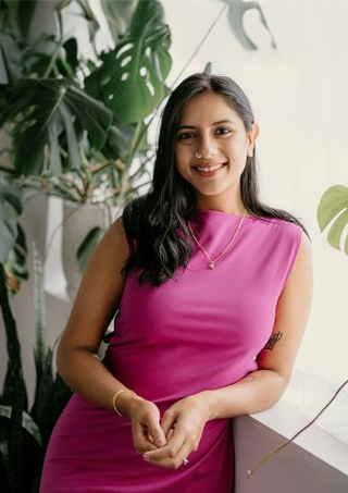 A clinician standing next to a plant.